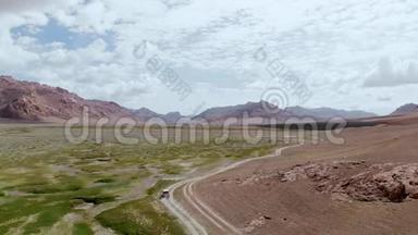 在4x4路的高空，汽车沿着干旱的沙漠山脉上的砾石小径行驶。 帕米尔公路丝绸之路旅行